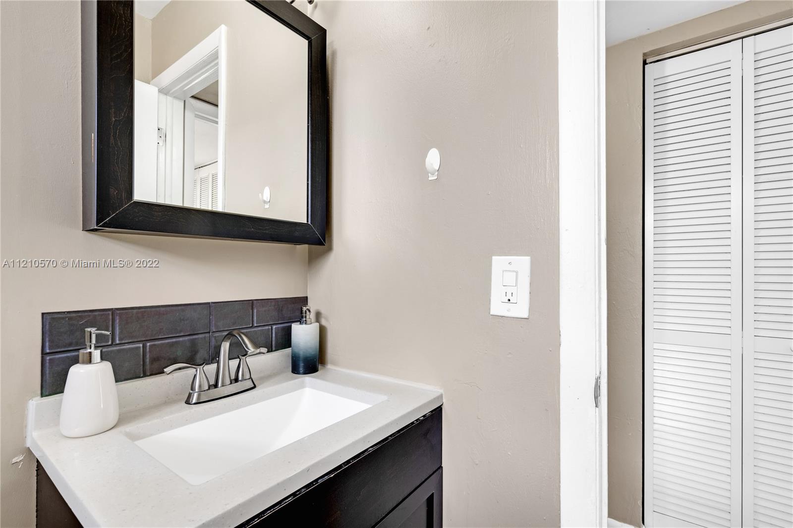 9459 Southwest 76th Street, Unit R7 Miami, FL 33173 - Photo 20 of 24 a bathroom with a sink vanity and a mirror