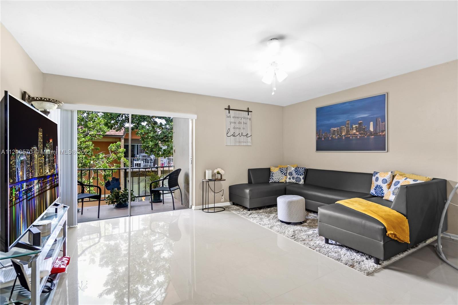 9459 Southwest 76th Street, Unit R7 Miami, FL 33173 - Photo 9 of 24 a living room with furniture a flat screen tv and a floor to ceiling window