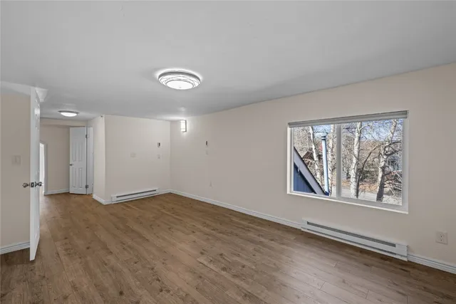 an empty room with wooden floor and windows