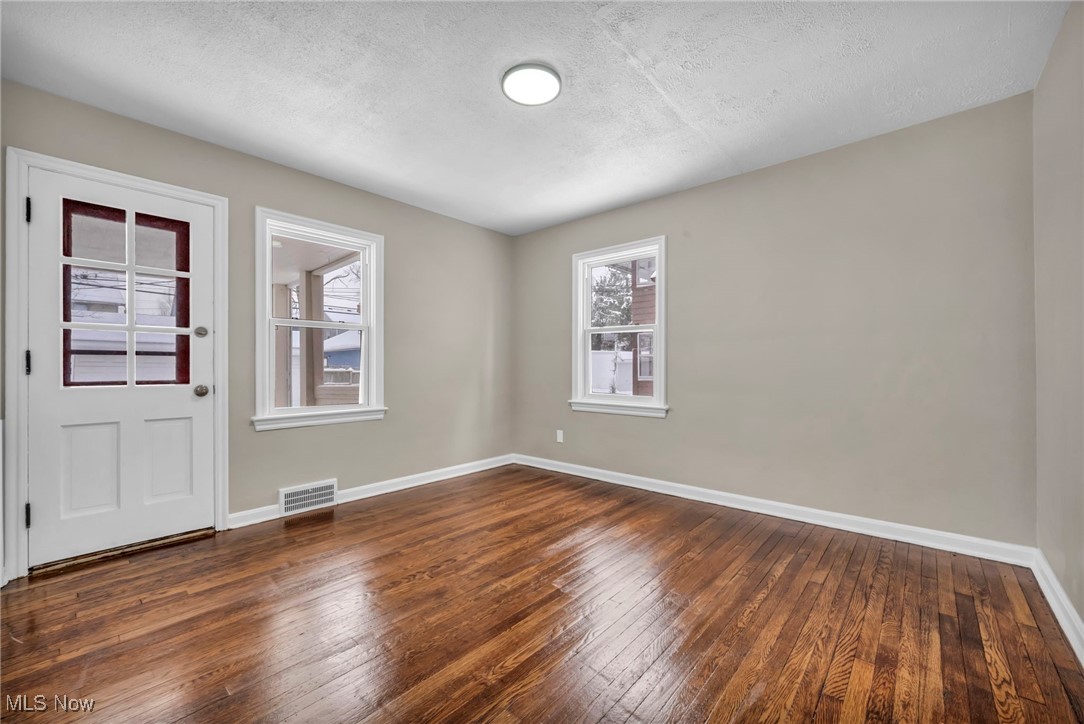 13614 Cedar Road Cleveland, OH 44118 - Photo 15 of 46 Empty room with baseboards, a textured ceiling, visible vents, and dark wood-style flooring