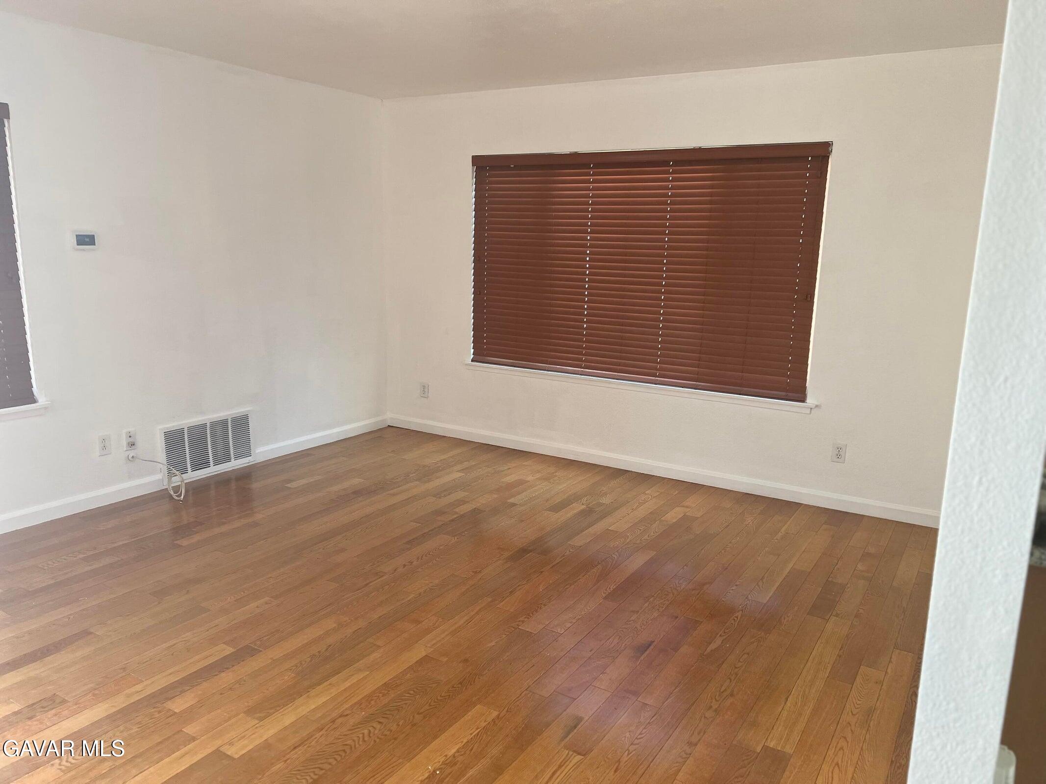42901 Alep Street Lancaster, CA 93536 - Photo 3 of 11 an empty room with wooden floor and windows