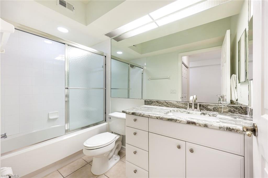10921 Santa Margherita Road, Unit 103 Estero, FL 34135 - Photo 15 of 38 a bathroom with a granite countertop sink toilet mirror and shower