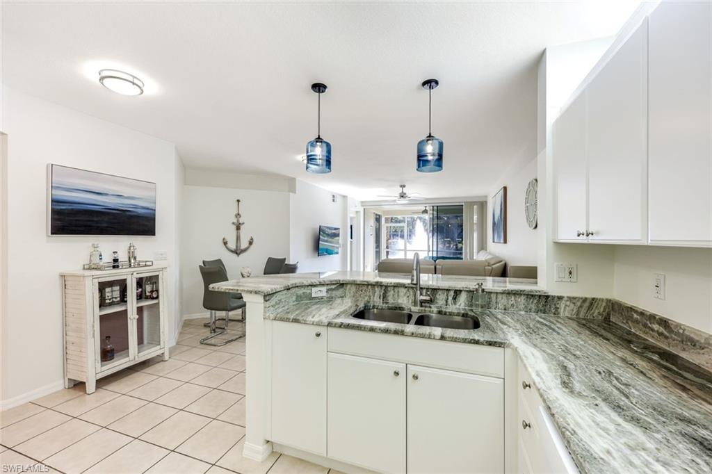 10921 Santa Margherita Road, Unit 103 Estero, FL 34135 - Photo 3 of 38 a kitchen with stainless steel appliances granite countertop a stove top oven a sink a counter space and cabinets
