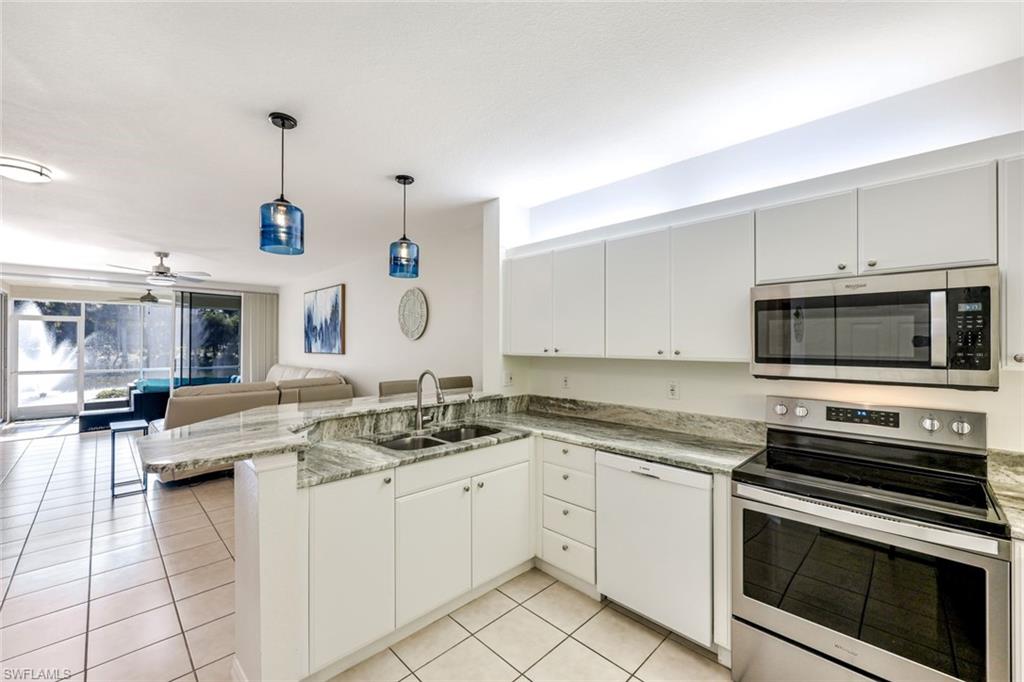 10921 Santa Margherita Road, Unit 103 Estero, FL 34135 - Photo 5 of 38 a kitchen with a stove microwave and cabinets