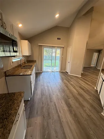 a kitchen with granite countertop wooden floors and wide window