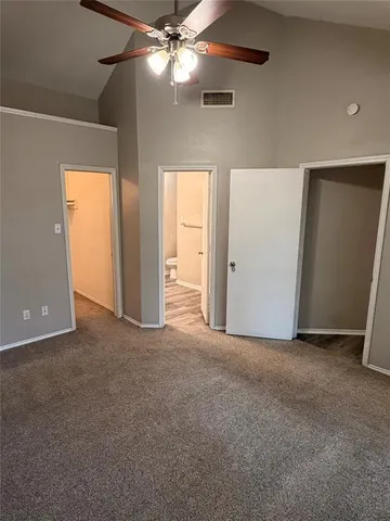 an empty room with closet and a chandelier fan