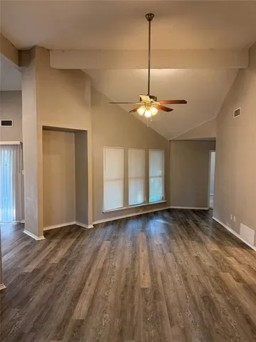 a view of an empty room with wooden floor fridge and a window