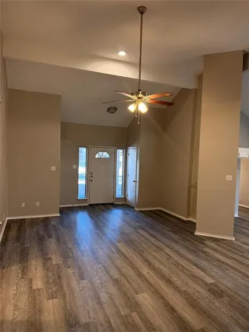 a view of an empty room with window and wooden floor