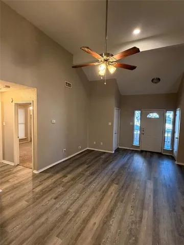 a view of an empty room with window and wooden floor