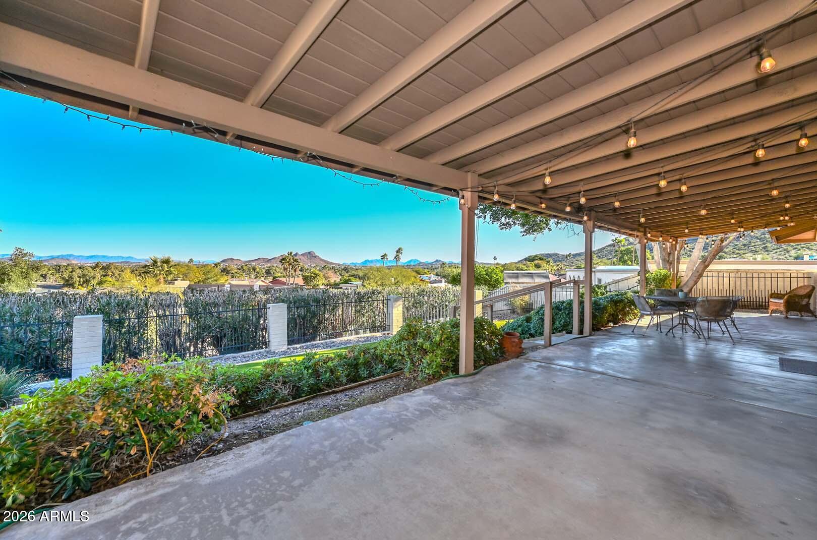 13013 North Surrey Circle Phoenix, AZ 85029 - Photo 26 of 36 a view of a patio with a table and chairs under an umbrella with a big yard