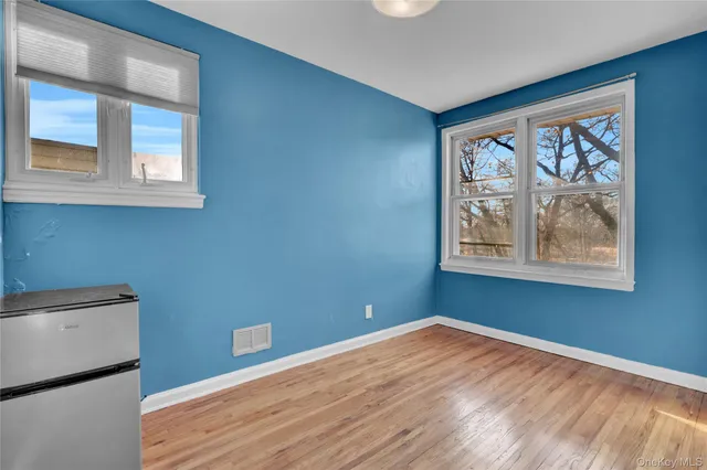 a view of empty room with window and wooden floor