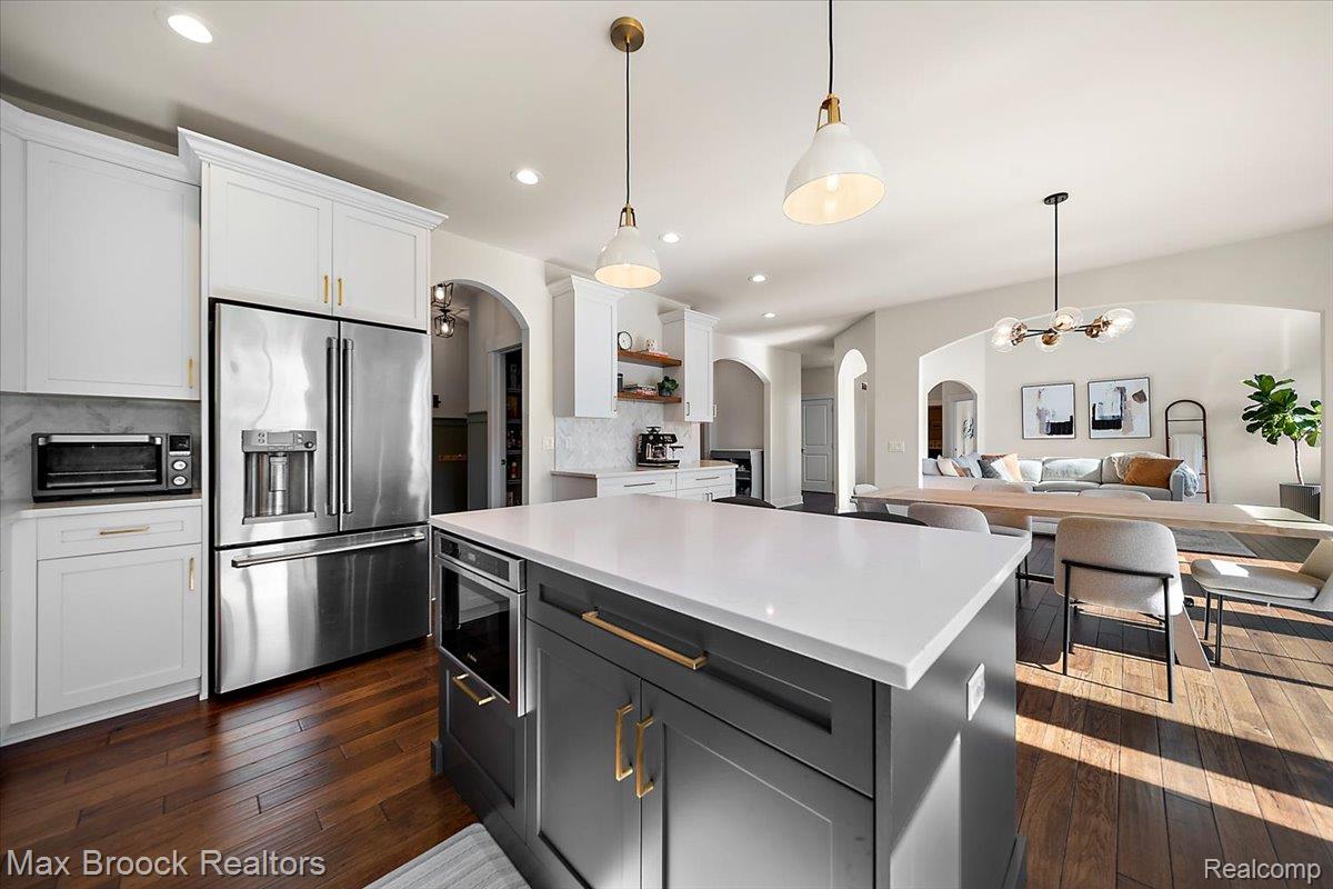 1942 Nottingham Drive Rochester, MI 48307 - Photo 23 of 97 Contemporary kitchen featuring a large central island with a solid surface countertop, integrated microwave, and dark cabinetry with gold-tone hardware