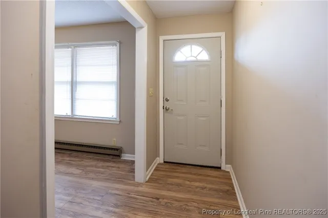 a view of an empty room with wooden floor and a window