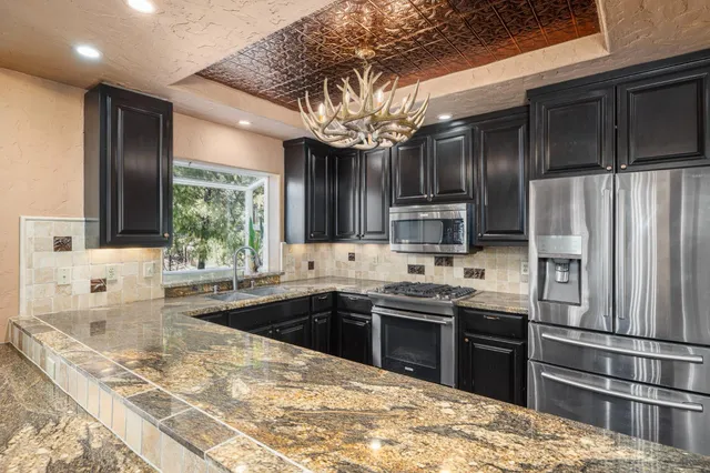 a large kitchen with granite countertop a large counter top space appliances and cabinets