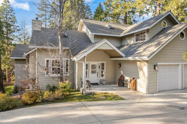 a view of a house with a yard and large trees