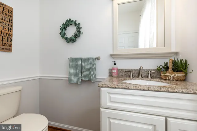 a bathroom with a granite countertop sink and a toilet