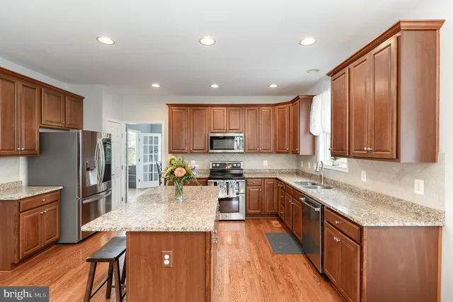 a kitchen with granite countertop stainless steel appliances a refrigerator a stove top oven cabinets a sink and a refrigerator