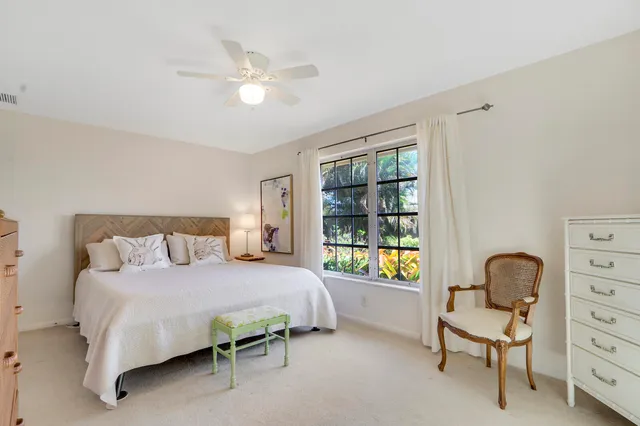 a bedroom with a bed a chair and a large window