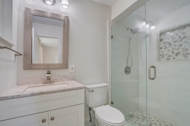 a bathroom with a granite countertop sink toilet a mirror and shower