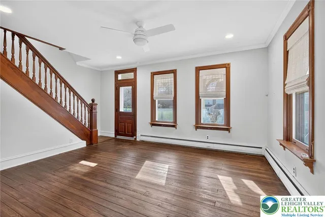 a view of an empty room with window and wooden floor