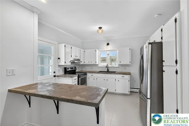 a kitchen with stainless steel appliances a refrigerator sink and white cabinets