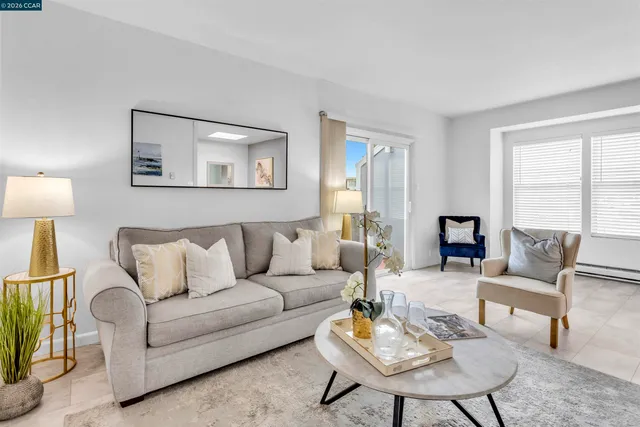 a living room with furniture a lamp on a table and a window