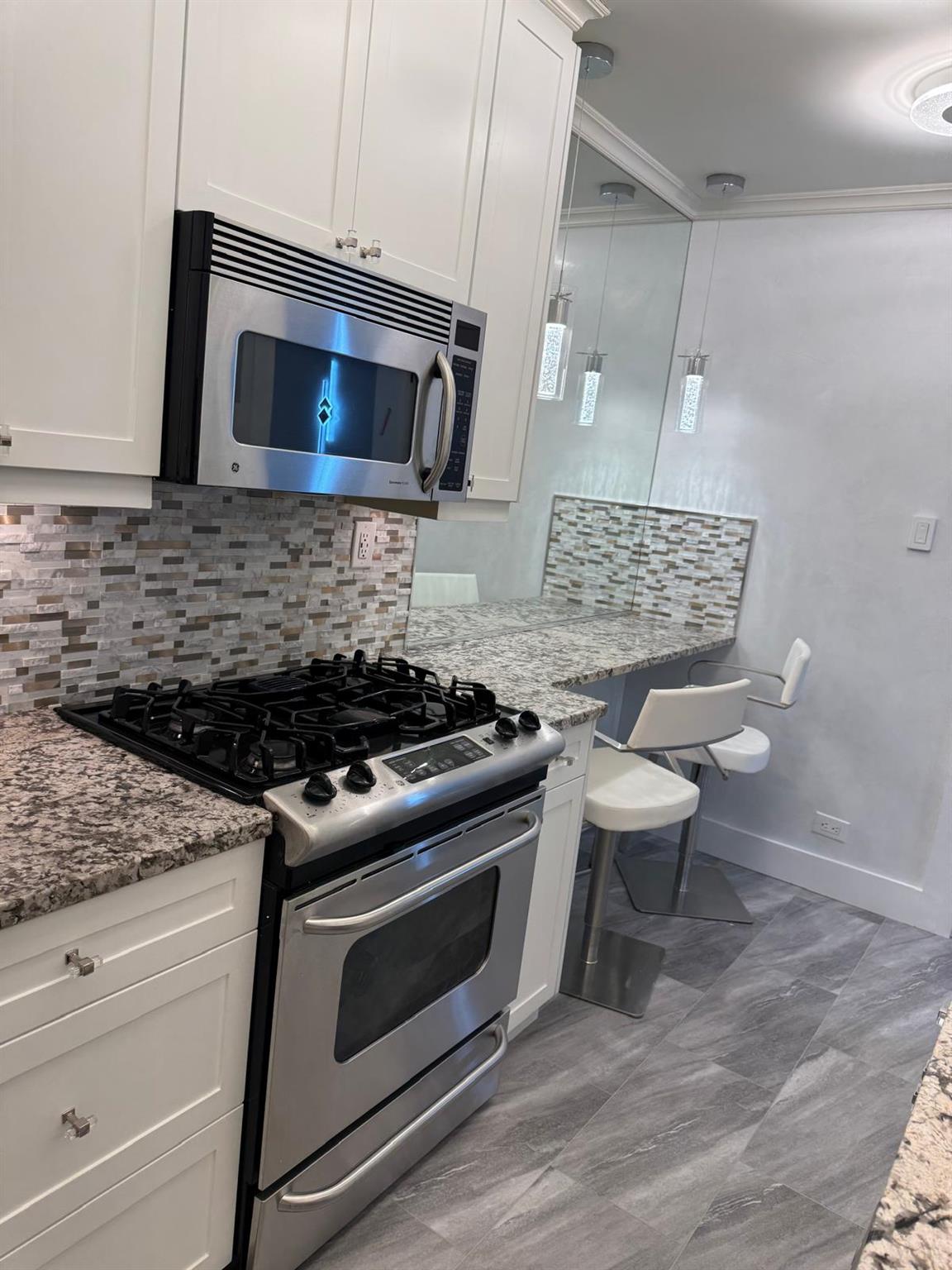 595 West End Avenue, Unit 3D Manhattan, NY 10024 - Photo 21 of 28 Kitchen with white cabinets, backsplash, light stone countertops, and stainless steel appliances