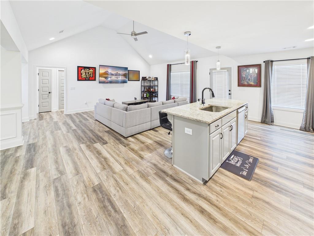 52 Owens Road Fort Mitchell, AL 36856 - Photo 13 of 29 Open-concept living space featuring wood-finish flooring, a kitchen island with a light-colored countertop and undermount sink, vaulted ceilings, and recessed lighting