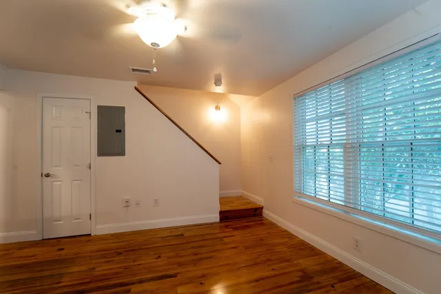 a view of an empty room with wooden floor and a window