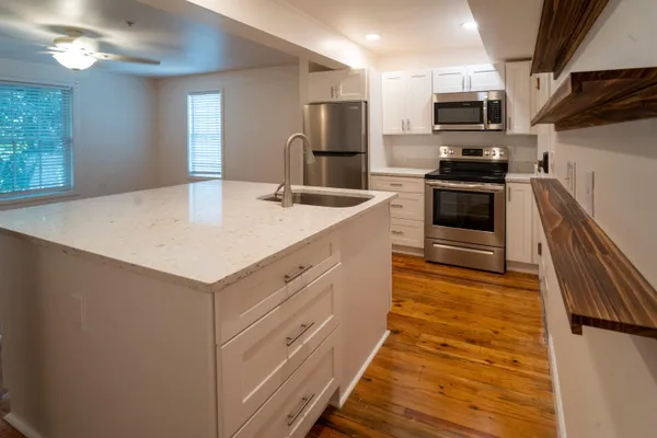 a kitchen with kitchen island white cabinets and stainless steel appliances
