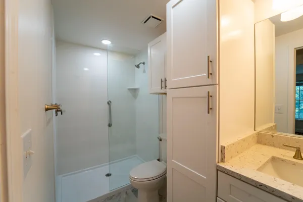 a bathroom with a granite countertop sink toilet and shower