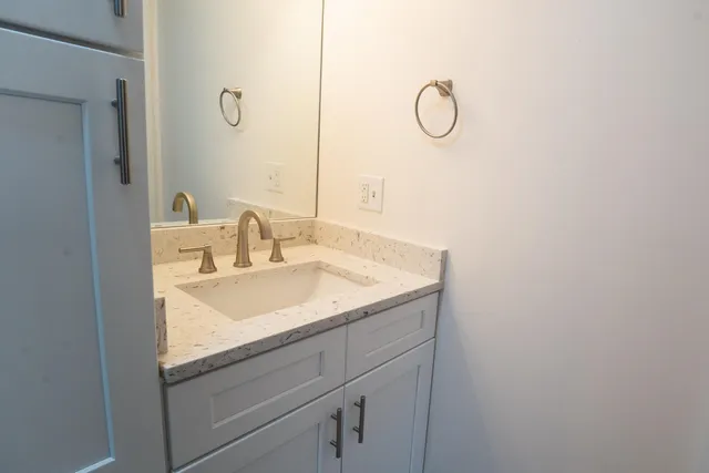 a bathroom with a granite countertop sink and mirror with a mirror