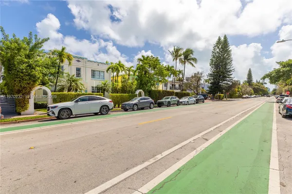 a view of a street with cars on both side of the house