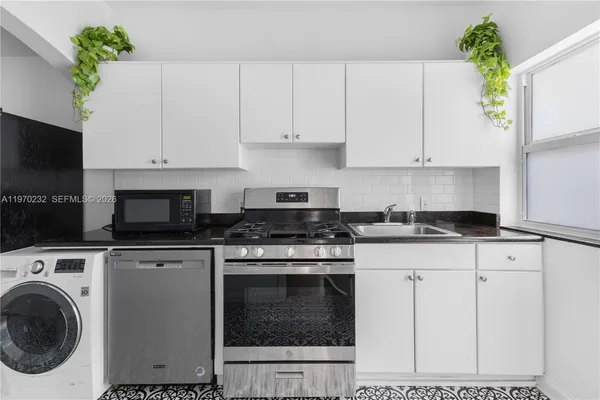 a kitchen with granite countertop white cabinets and stainless steel appliances