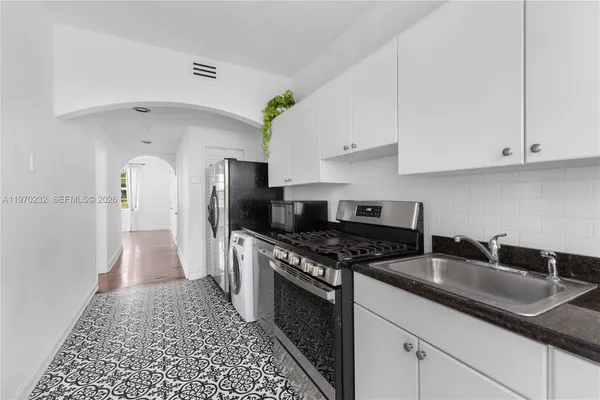 a kitchen with granite countertop a sink a stove and refrigerator