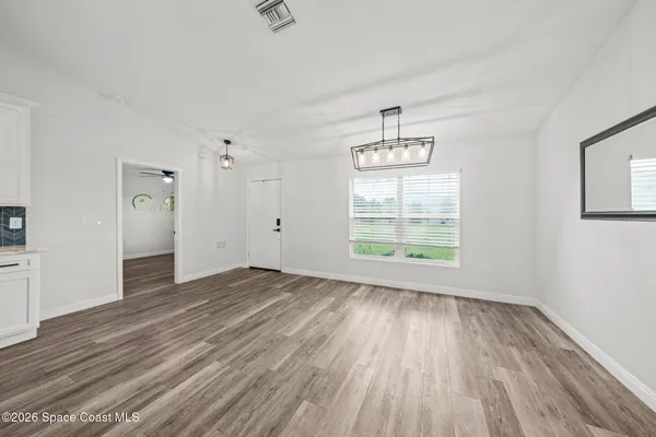 an empty room with wooden floor cabinet and windows