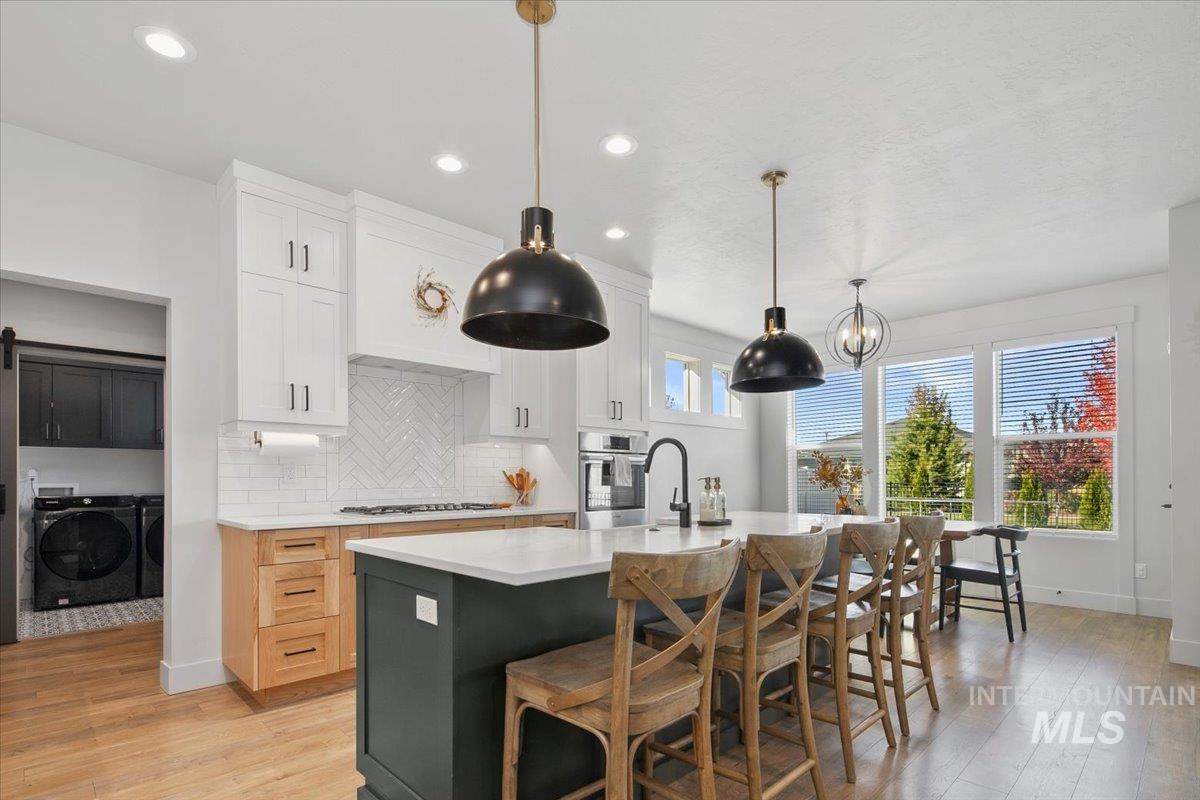 4150 East Fratello Street Meridian, ID 83642 - Photo 13 of 46 Kitchen featuring decorative backsplash, white cabinetry, light wood-type flooring, decorative light fixtures, and recessed lighting