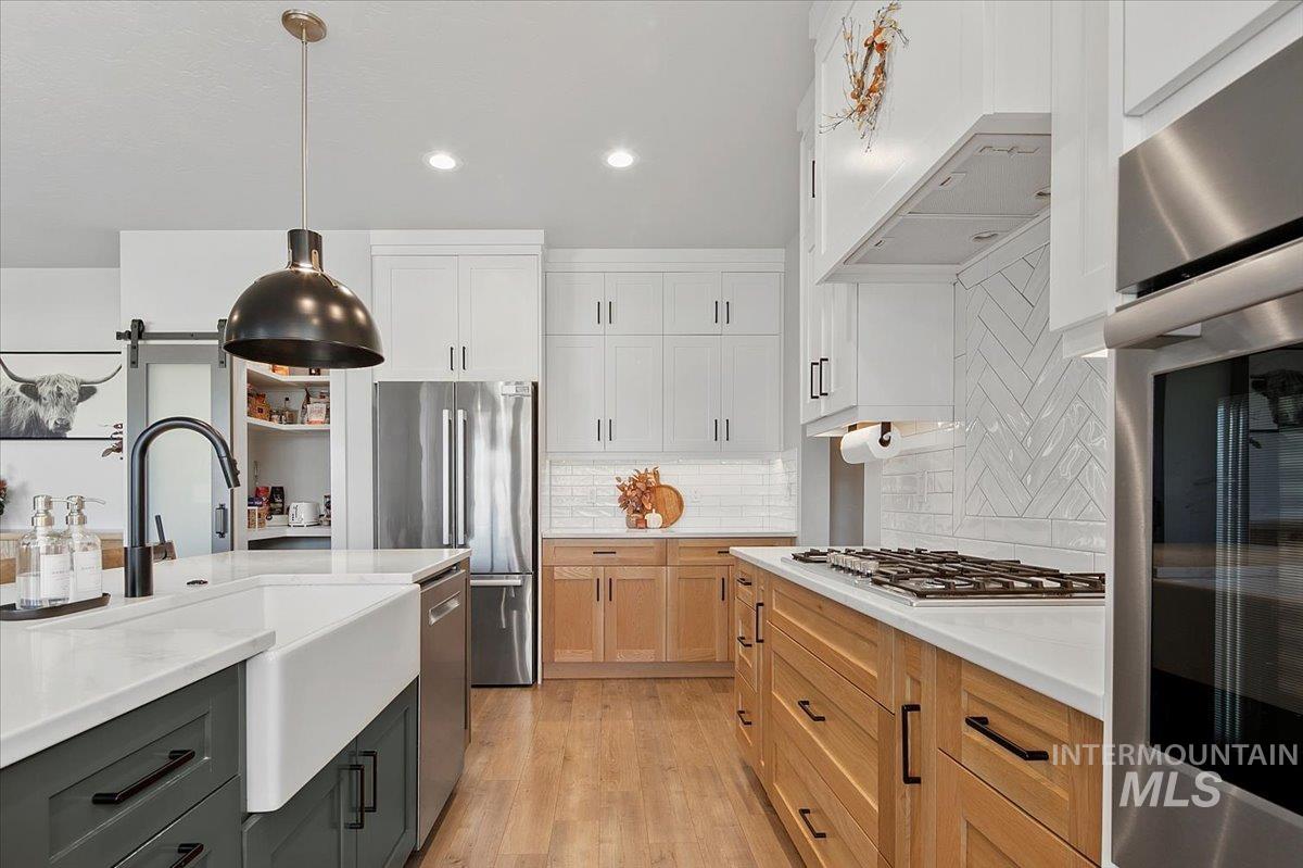 4150 East Fratello Street Meridian, ID 83642 - Photo 14 of 46 Kitchen featuring stainless steel appliances, pendant lighting, light wood-type flooring, white cabinets, and recessed lighting
