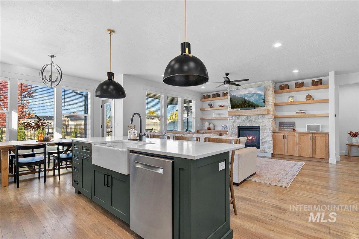 4150 East Fratello Street Meridian, ID 83642 - Photo 18 of 46 Kitchen with green cabinets, a kitchen island with sink, stainless steel dishwasher, a fireplace, and a ceiling fan