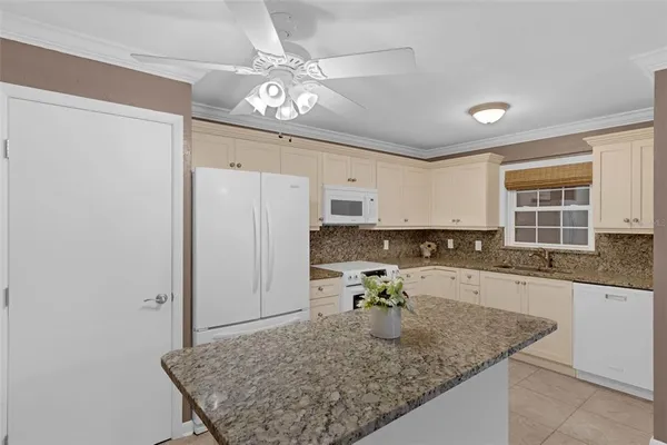 a large white kitchen with granite countertop a sink dishwasher a stove and white cabinets with wooden floor