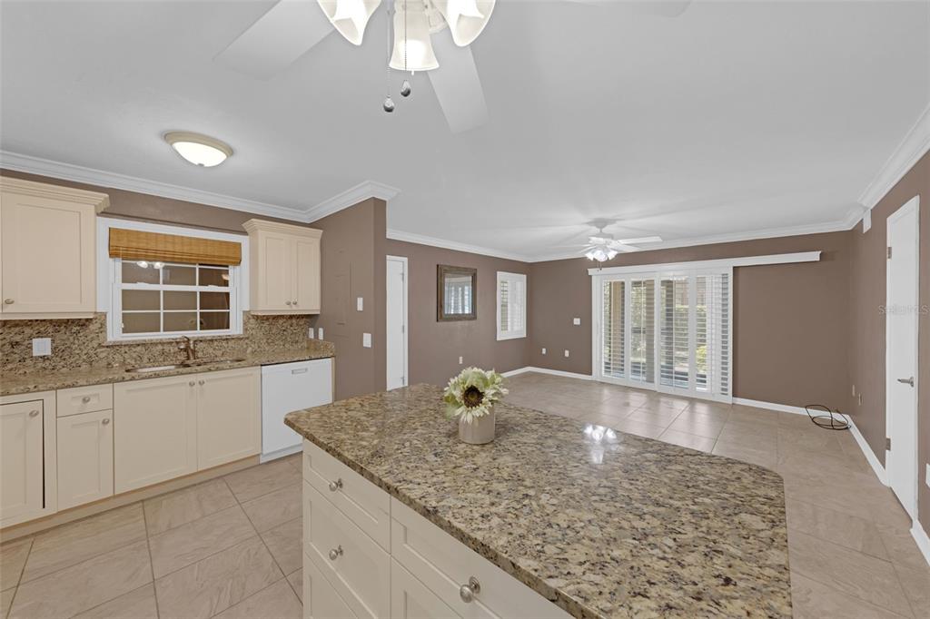Undisclosed Address Astor, FL 32102 - Photo 10 of 28 a large white kitchen with granite countertop a sink dishwasher a stove and white cabinets with wooden floor