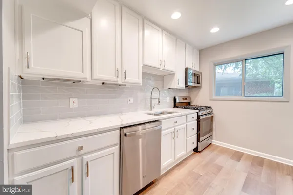 a kitchen with stainless steel appliances granite countertop white cabinets a sink and a stove