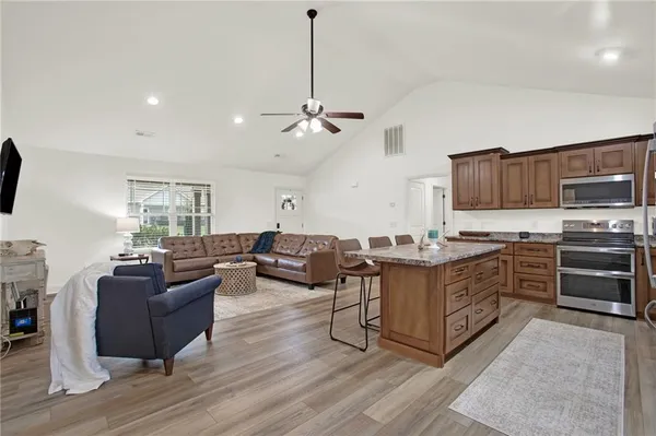 a kitchen with kitchen island granite countertop a stove top oven a sink dishwasher a dining table and chairs with wooden floor