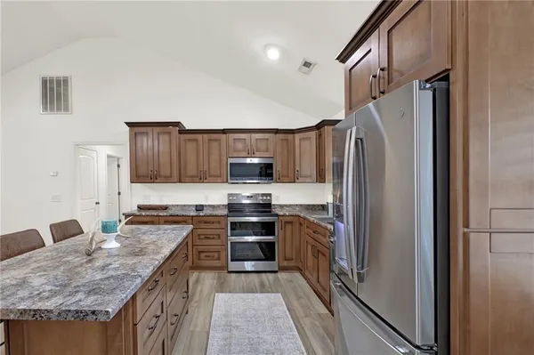 a kitchen with stainless steel appliances granite countertop a refrigerator a stove and a sink