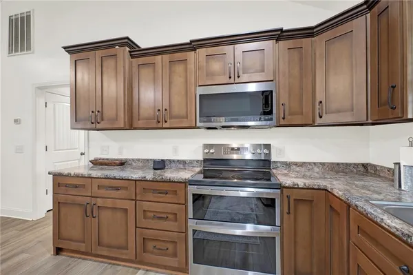 a kitchen with granite countertop a stove microwave and oven