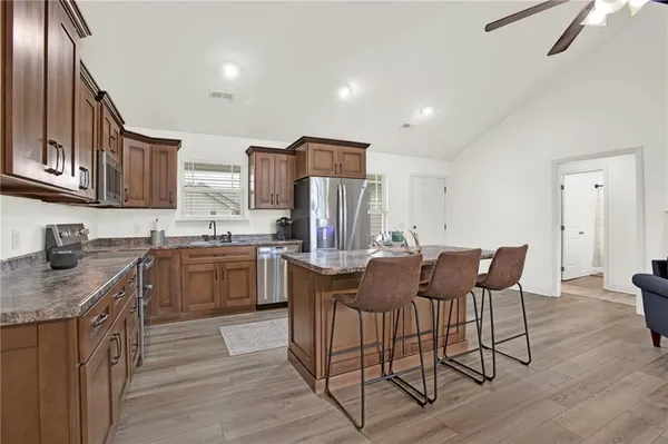 a kitchen with stainless steel appliances granite countertop a stove top oven a sink dishwasher a dining table and chairs with wooden floor