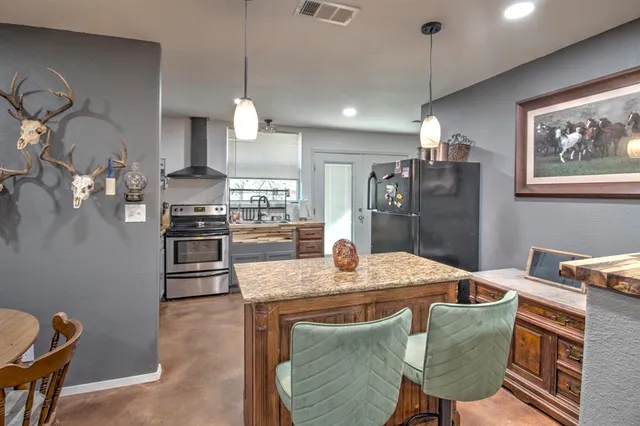 a kitchen with granite countertop kitchen island stainless steel appliances sink stove dining table and chairs