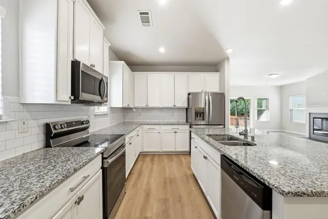 a kitchen with stainless steel appliances granite countertop a sink stove microwave and refrigerator