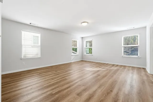 an empty room with wooden floor and windows