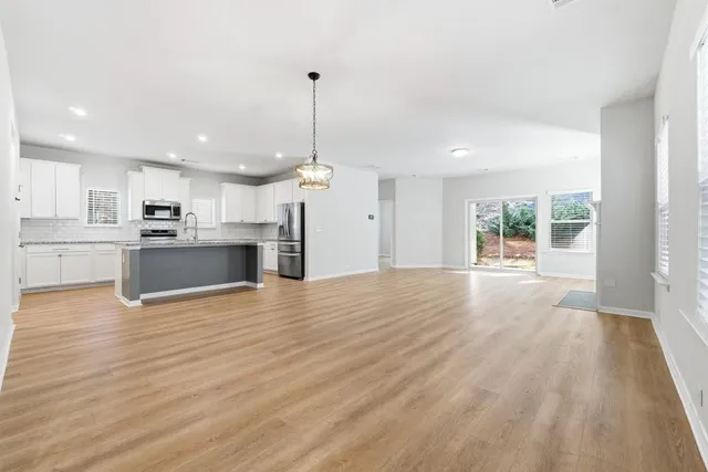 an empty room with wooden floor and large windows